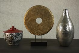 A modern carved gold painted disc on stand along with a silver glaze vase with stippled design and a