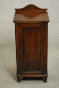 A Victorian walnut bedside cabinet, with a shaped gallery back over a single cupboard door, on