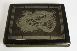 A Japanese black lacquer covered photo album with silver dragon design containing early 20th century
