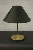 A contemporary brass table lamp, with a slender stem and a circular base, with a black shade. H.60