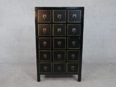 A contemporary black lacquered Chinese apothecary style cabinet, with five rows of three square
