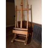 A beech adjustable studio easel with H frame ftted with base drawer on sled supports resting on
