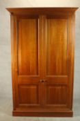A late 20th century cherrywood wardrobe, with a pair of panelled doors opening to reveal hanging