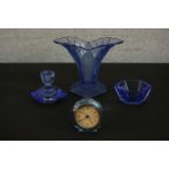 A group of circa 1930s press moulded blue glass items, including a desk clock, a vase, a bowl and