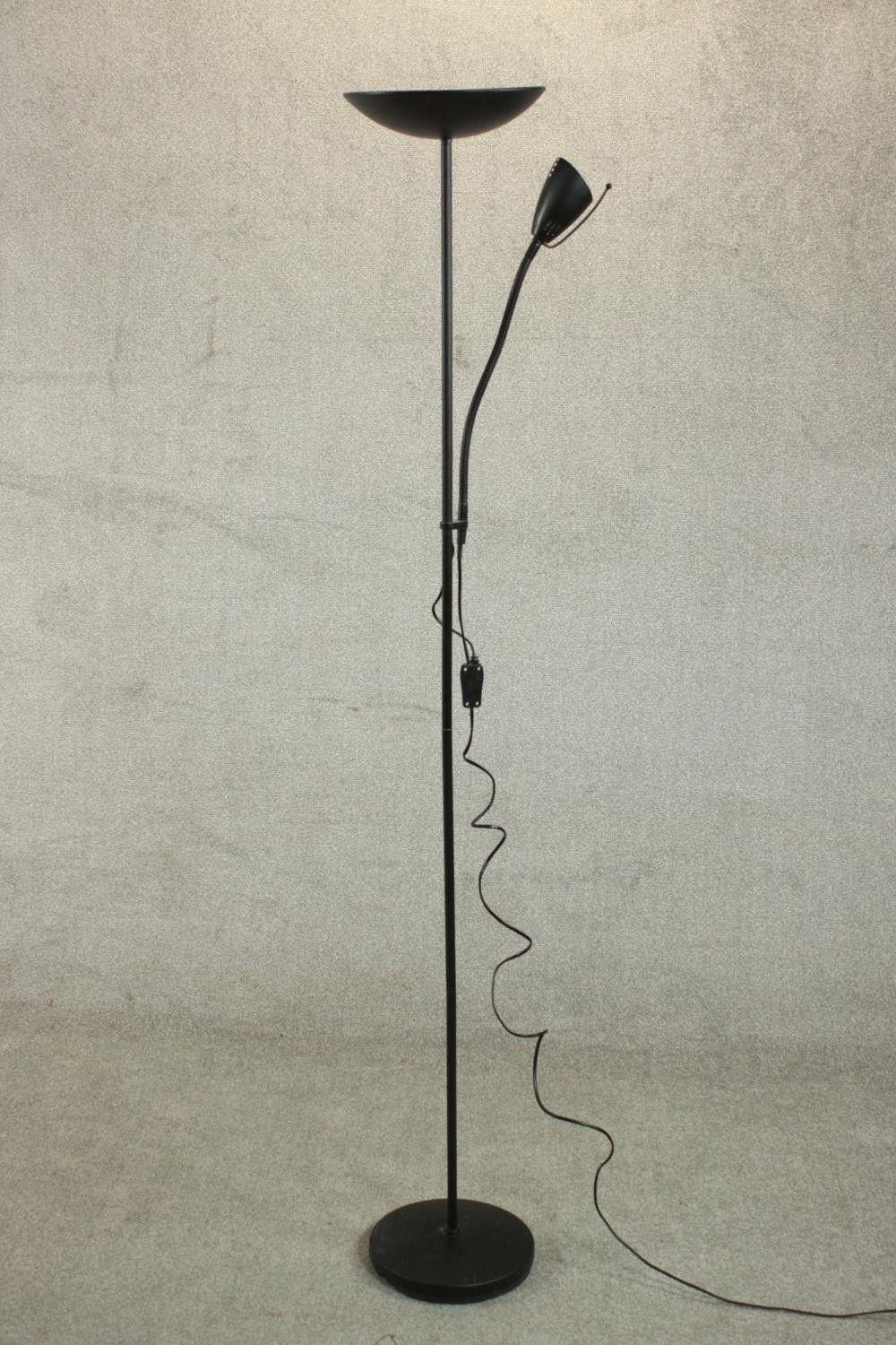 A contemporary ebonised uplighter and reading lamp, the reading lamp on an adjustable arm, on a