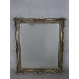 A contemporary mirror with a sivered frame, of rectangular form, the frame with scrolling and