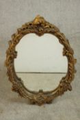 A mid 20th century Rococo style gilt mirror, of oval form, the frame with scrolling foliate designs.
