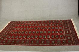 A Bokhara carpet with elephant's foot motifs on a burgundy ground within floral multiple borders.
