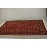 A Bokhara carpet with elephant's foot motifs on a burgundy ground within floral multiple borders.