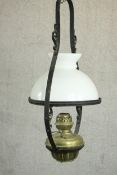 A 19th century colonial style wrought iron and brass hanging oil lamp with an opaline glass shade.