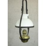 A 19th century colonial style wrought iron and brass hanging oil lamp with an opaline glass shade.