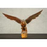 A 20th century carved wood eagle sculpture, with wings spread, standing on a rocky outcrop. H.40 W.