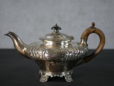 A Georgian silver tea pot with repousse floral and foliate design and shell form feet, hallmarked: