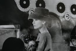 A black and white photo of Audrey Hepburn holding a dog in a smart hat by Hulton Archive.