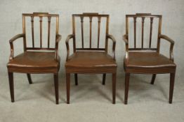 A set of three Sheraton style mahogany open armchairs, upholstered with brown leather seats, studded