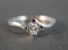 A 9 carat white gold cross over diamond solitaire ring, set to centre with a round brilliant cut