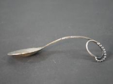 A Georg Jensen Danish silver spoon, pattern 41, with a curved and beaded scrolling handle and leaf