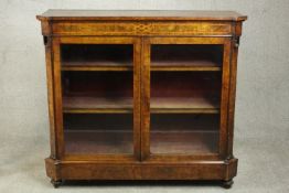 A Victorian figured walnut and marquetry inlaid bookcase, with two glazed doors enclosing a purple