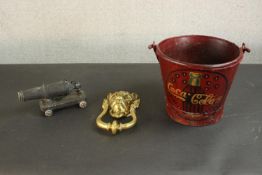 A large brass lion head door knocker along with a painted iron bucket with a coca cola design and an