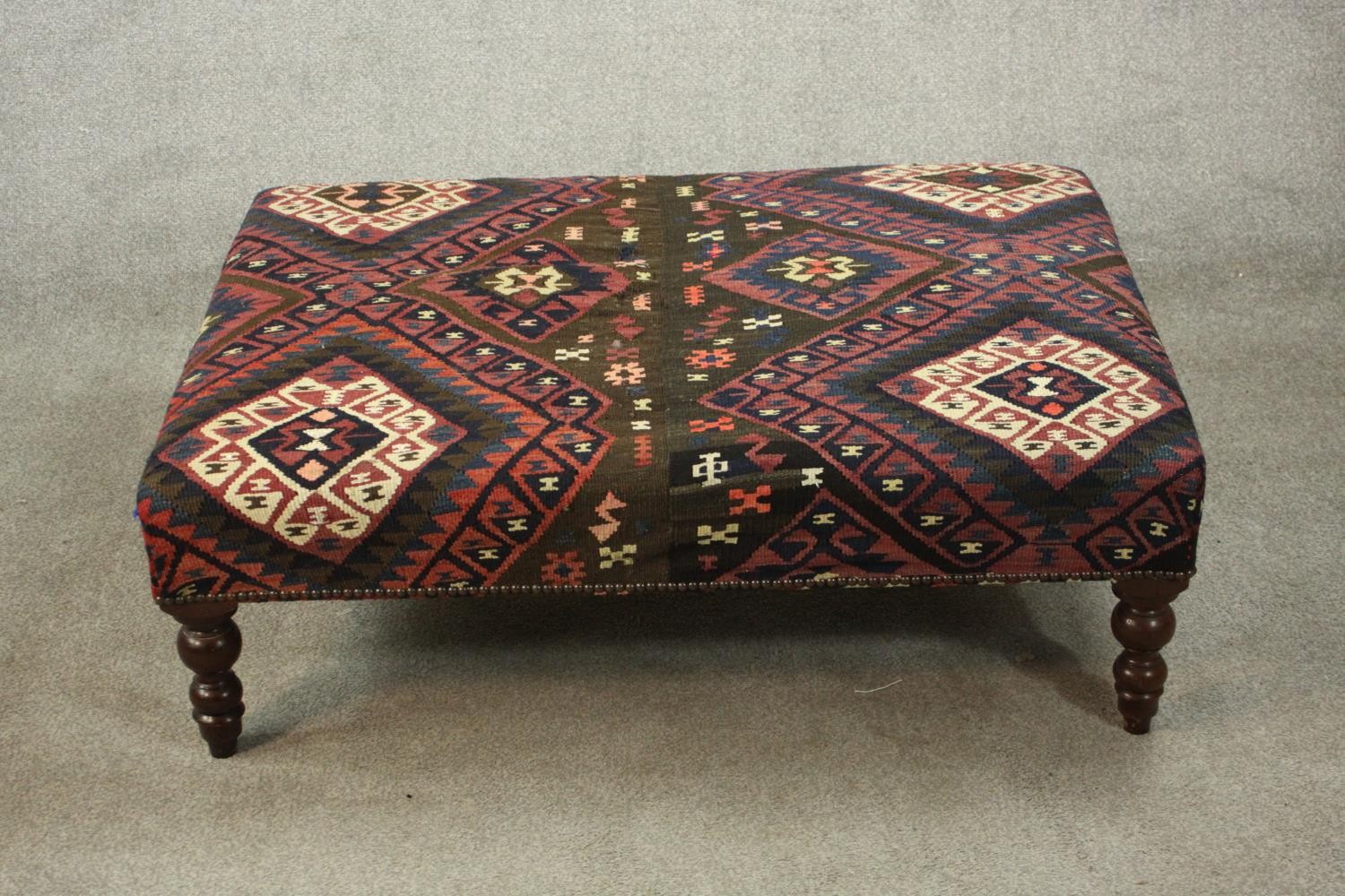 A contemporary footstool, of rectangular form upholstered in kilim fabric, on turned legs. H.33 W.