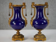 A pair of 19th century Sevres style cobalt blue porcelain and ormolu mounted bronze urns. The