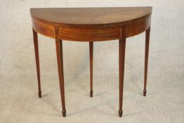 A George III style Edwardian mahogany demi lune card table, the foldover top crossbanded, with a