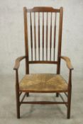 A beech stick back country armchair, with a woven seat, the legs joined by stretchers.