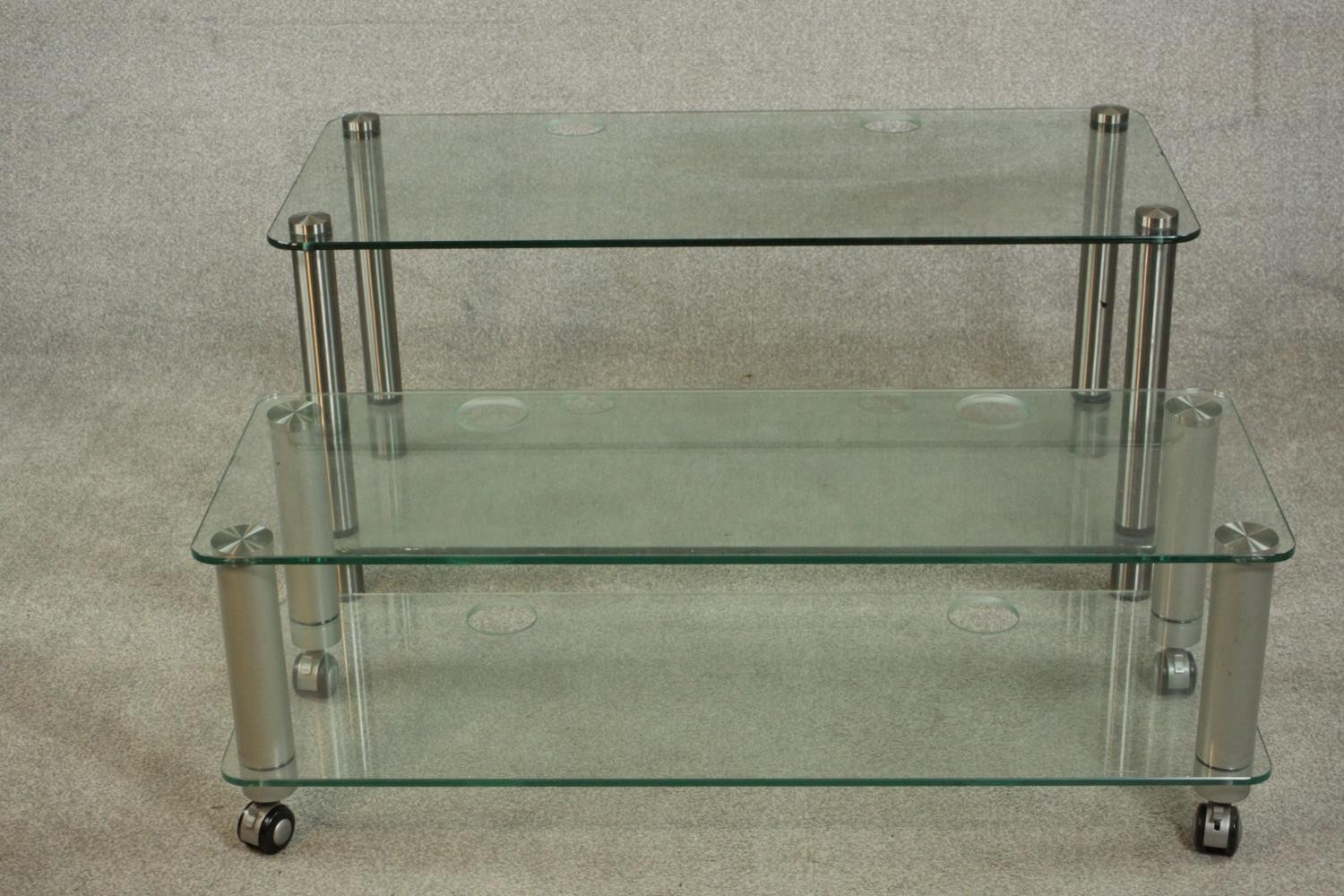 Two contemporary home entertainment stands, plate glass with rounded corners on cylindrical metal