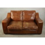 A late 20th century brown leather two seater sofa by Raft, with angular arms, on bun feet. H.86 W.