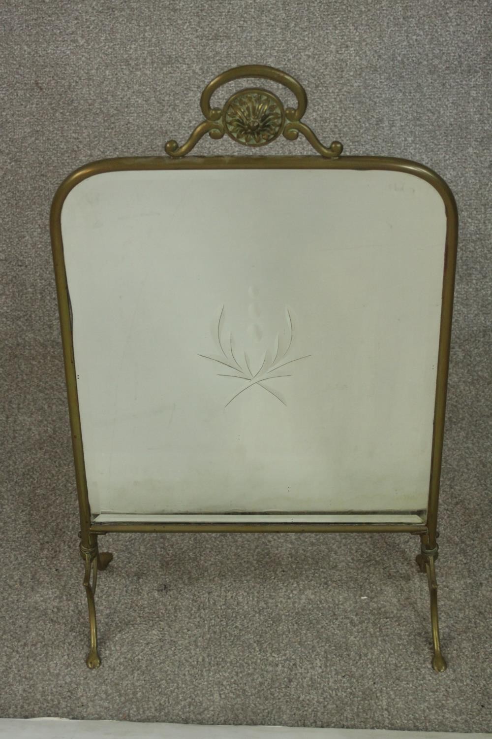 A circa 1900 brass mirrored fire screen, with engraved foliate design to the centre of the mirror