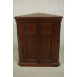 A George III walnut corner cabinet, with two panelled cupboard doors enclosing a white painted