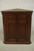A George III walnut corner cabinet, with two panelled cupboard doors enclosing a white painted
