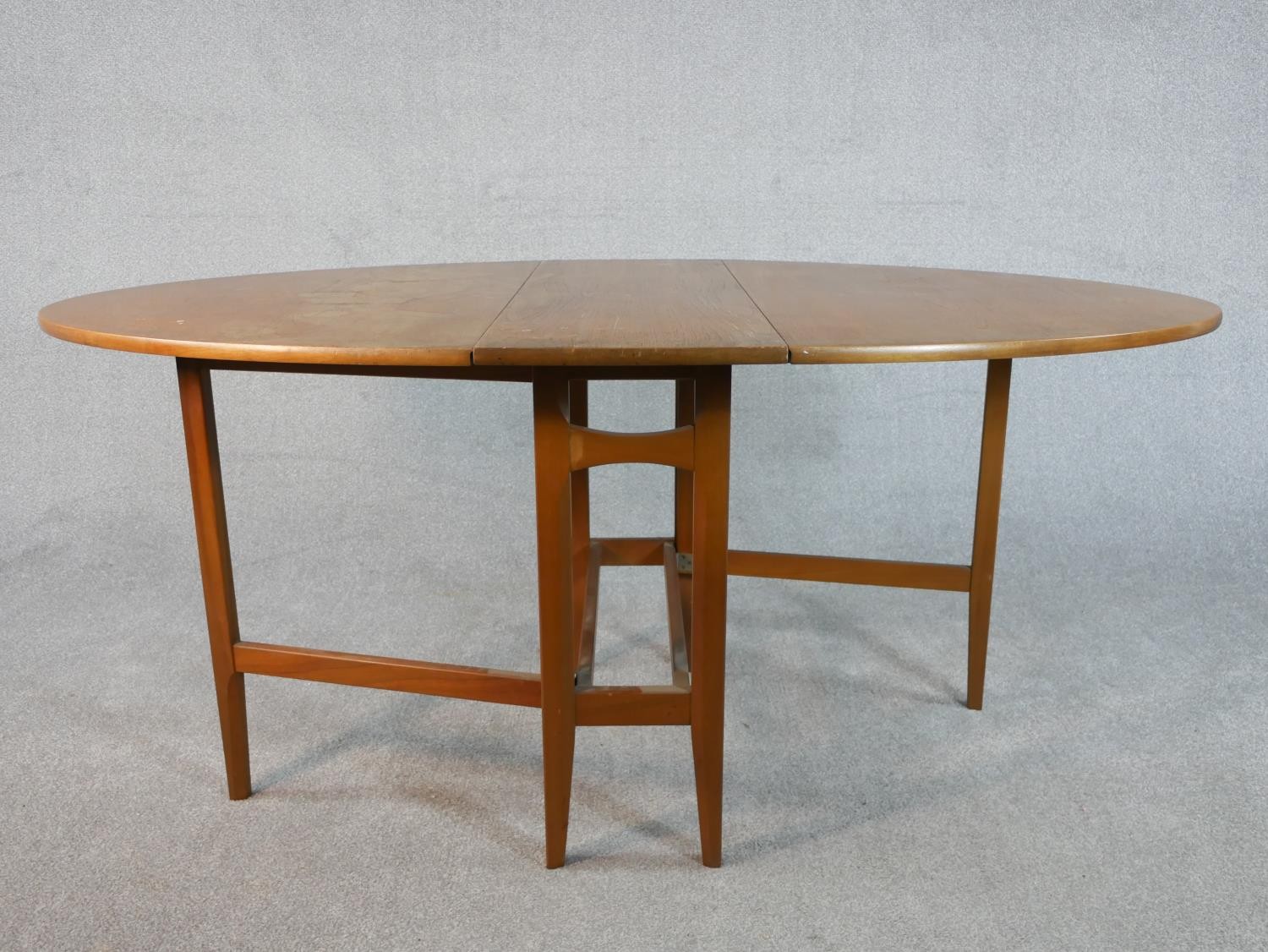 A late 20th century teak drop leaf dining table, the top of oval form with gateleg supports. H.74