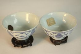 Two 19th century Chinese blue and white stylised foliate and floral design bowls on carved and