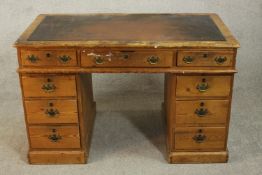 A late Victorian pine pedestal desk, with a brown leathert insert over an arrangement of nine