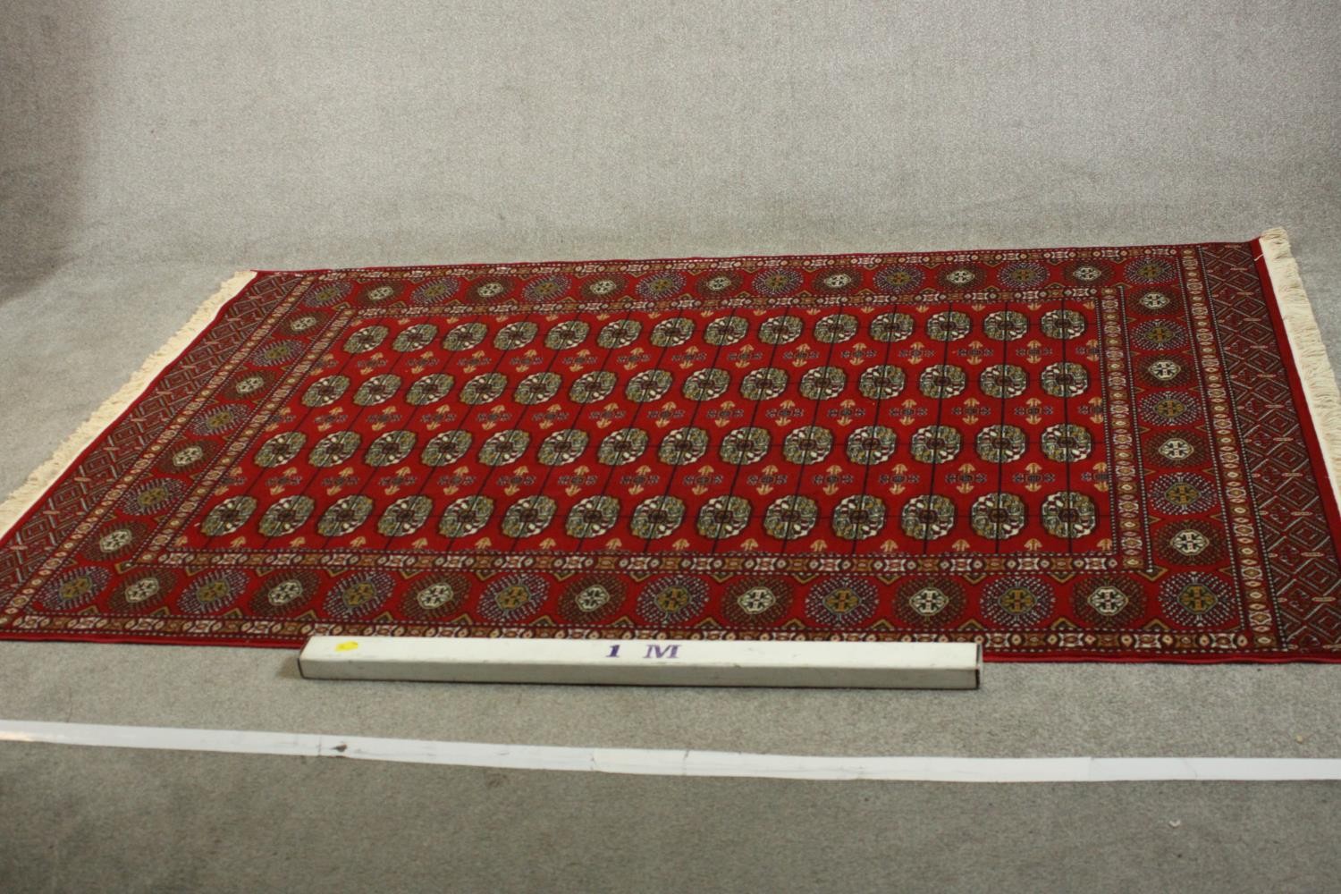 A Bokhara carpet with elephant's foot motifs on a burgundy ground within floral multiple borders. - Image 2 of 8