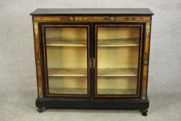 A Victorian ebonised and inlaid bookcase, with two glazed doors enclosing shelves, on a plinth