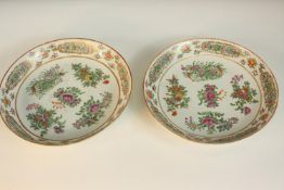A pair of Chinese famille rose porcelain plates, decorated with flowers and with gilded detail.