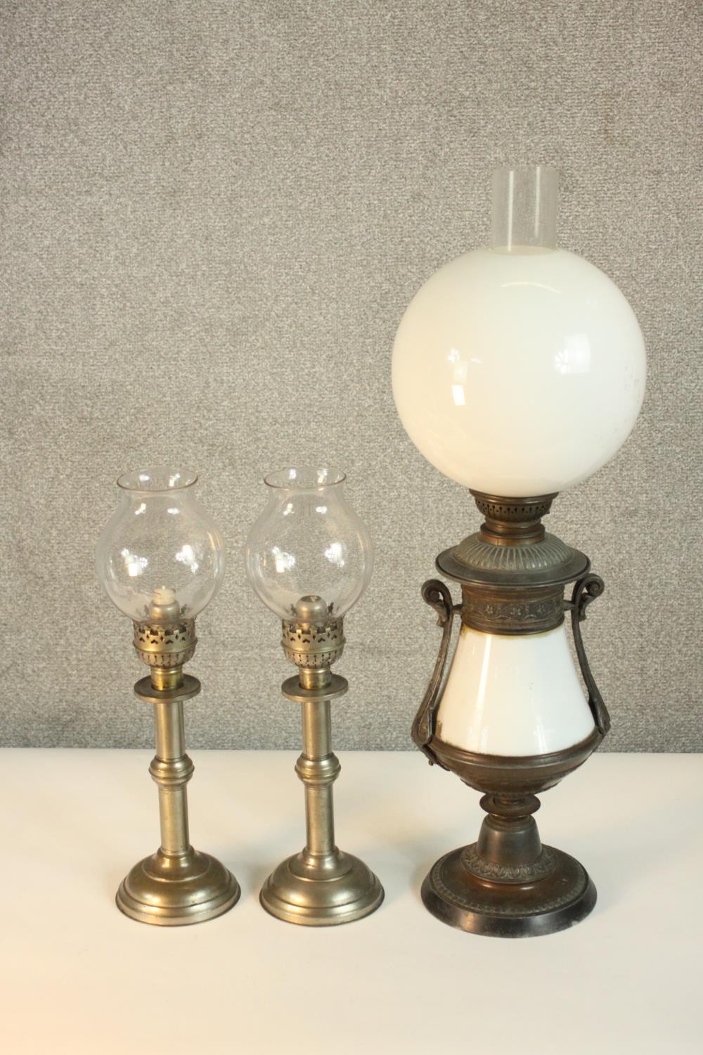 A pair of Victorian silver plated candlesticks, with glass storm shades, together with a converted