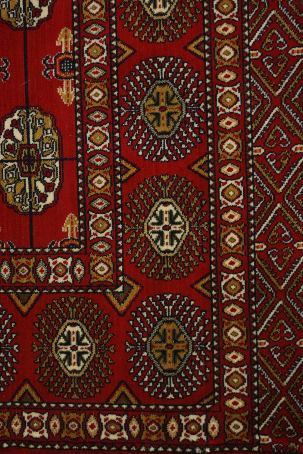 A Bokhara carpet with elephant's foot motifs on a burgundy ground within floral multiple borders. - Image 7 of 8
