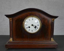 A late 19th/early 20th century mahogany and inlaid mantel clock, with a serpentine top, the