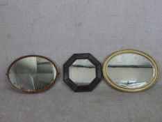 A collection of three wall mirrors, including an octagonal oak framed mirror, an oval mahogany