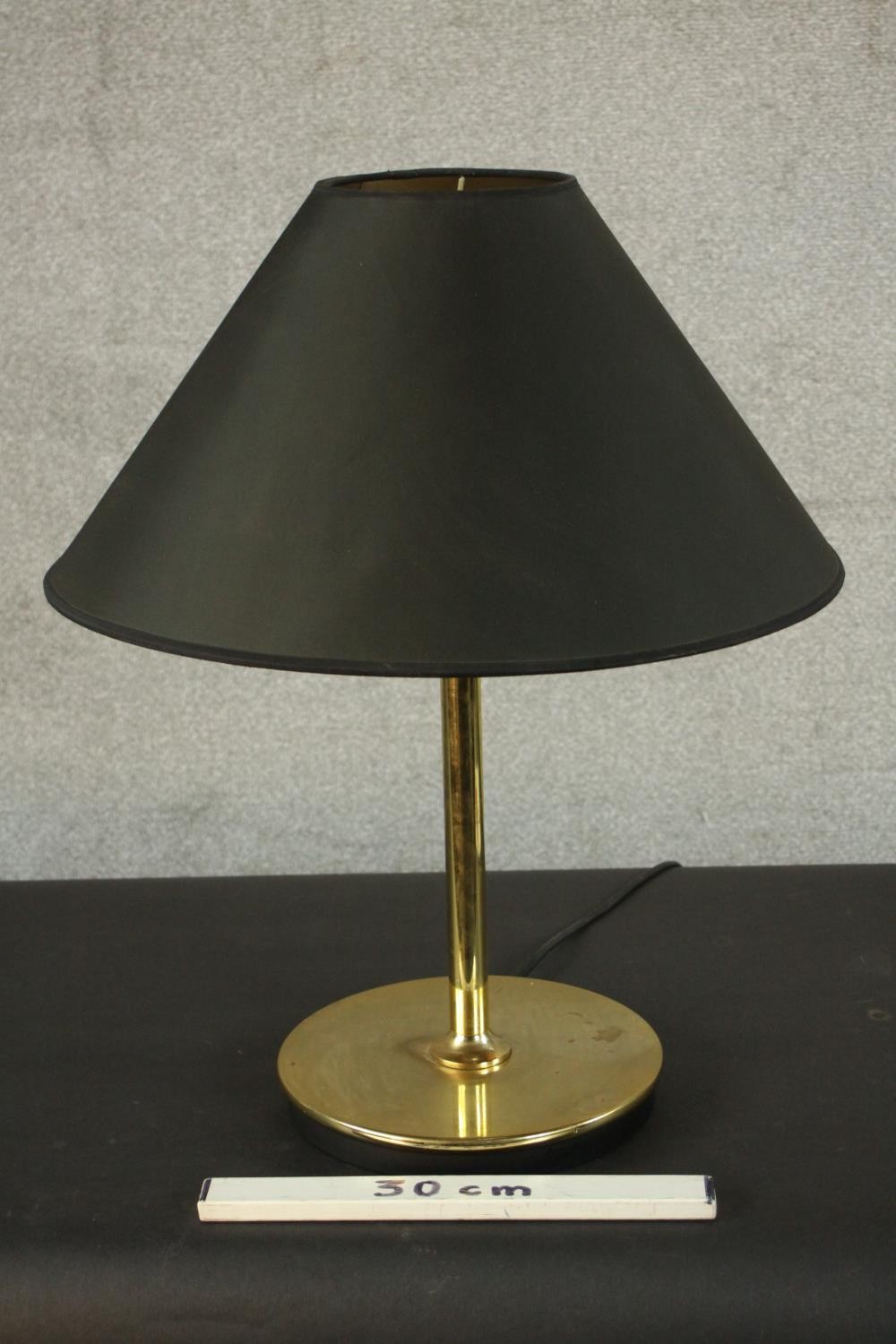 A contemporary brass table lamp, with a slender stem and a circular base, with a black shade. H.60 - Image 2 of 5