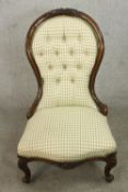 A Victorian walnut spoon back nursing chair, upholstered in patterned ivory fabric with a button