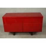 A contemporary red lacquered sideboard with two cupboard doors, on black lacquered supports. H.74