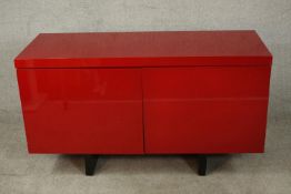 A contemporary red lacquered sideboard with two cupboard doors, on black lacquered supports. H.74