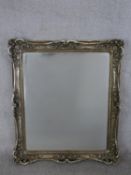 A contemporary mirror with a sivered frame, of rectangular form, the frame with scrolling and