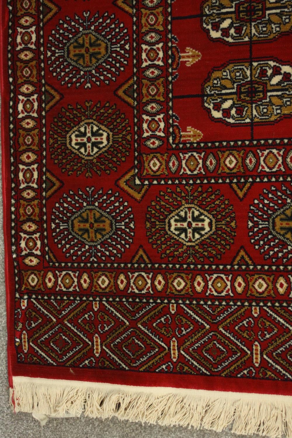 A Bokhara carpet with elephant's foot motifs on a burgundy ground within floral multiple borders. - Image 6 of 8