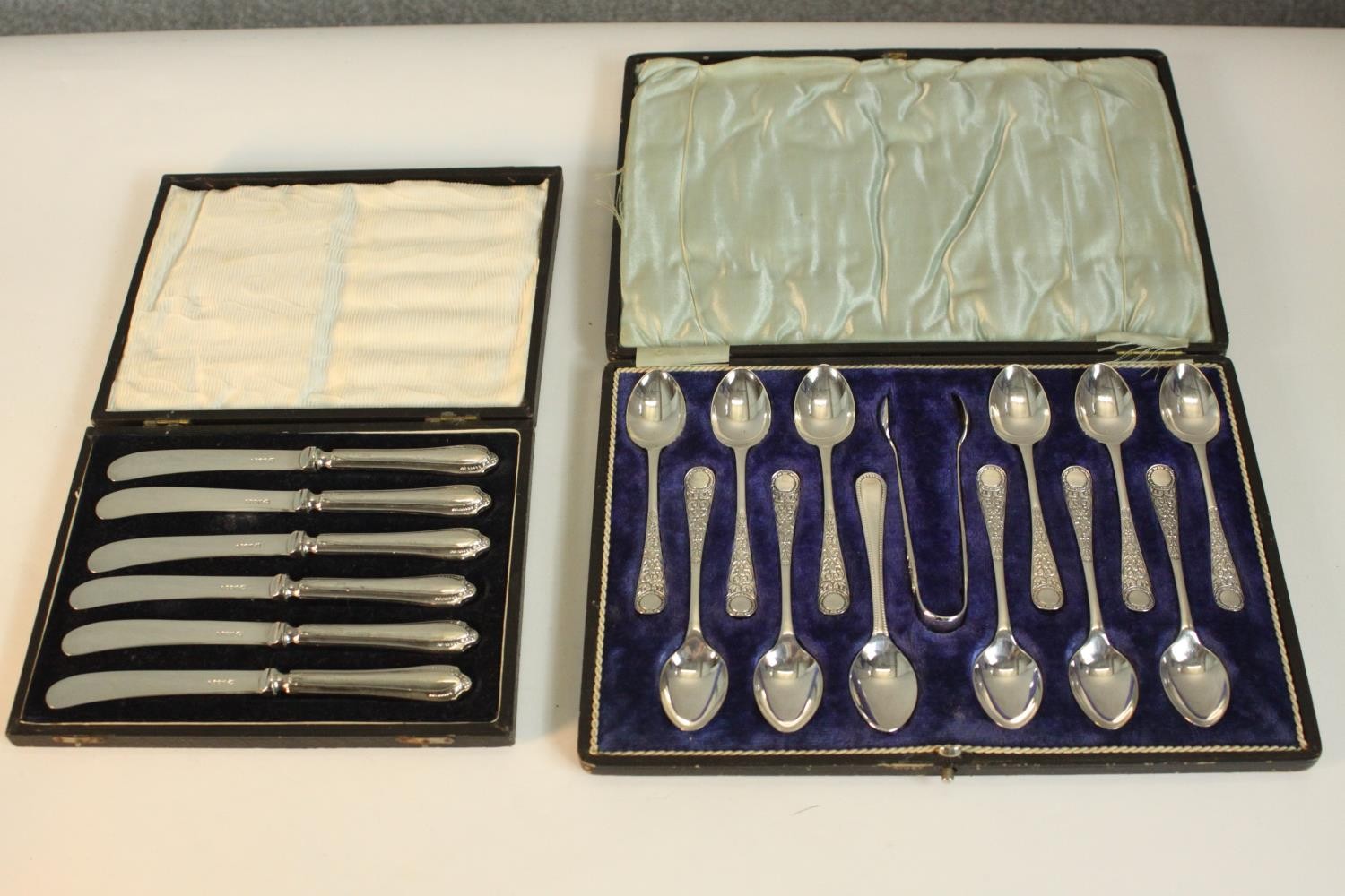 A leather cased set of coffee spoons and sugar tongs by Walker and Hall along with a cased set of