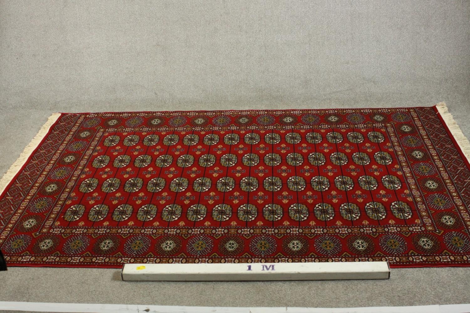 A Bokhara carpet with elephant's foot motifs on a burgundy ground within floral multiple borders. - Image 3 of 8